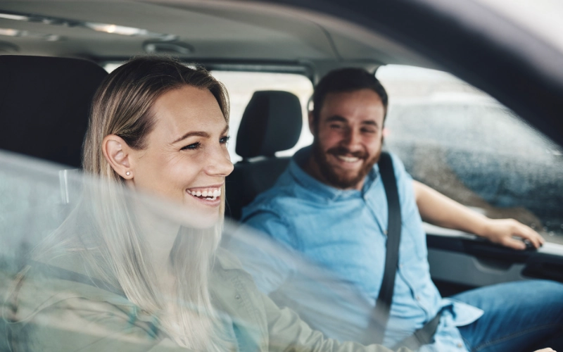 Pareja sonriendo dentro del coche