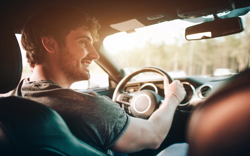 Pareja feliz sentada en el coche disfrutando de un viaje