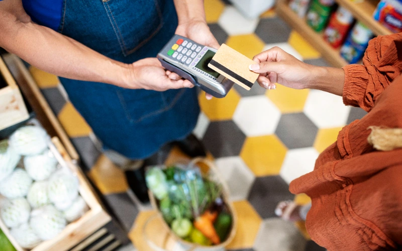 Comerciante ayudando a su cliente a pagar en la tienda