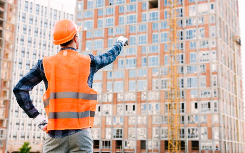 Trabajador de la construcción señalando un edificio en obra