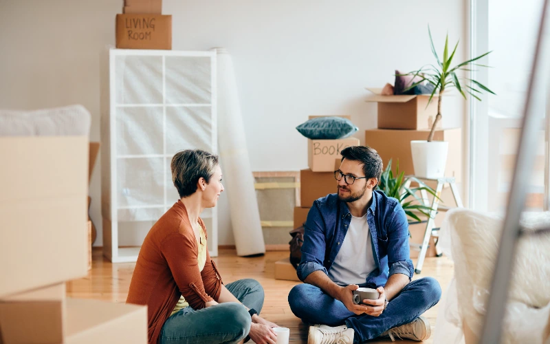 Pareja feliz hablando sentada en el suelo de su nuevo hogar