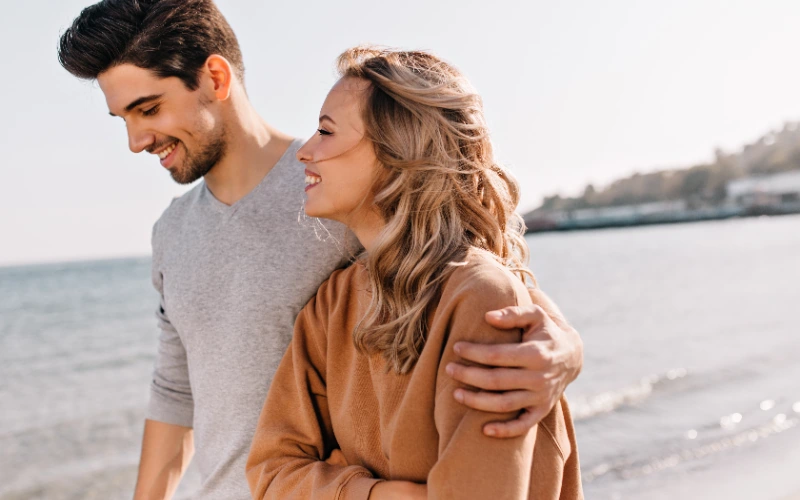 Pareja abrazada disfrutando de un paseo junto al mar