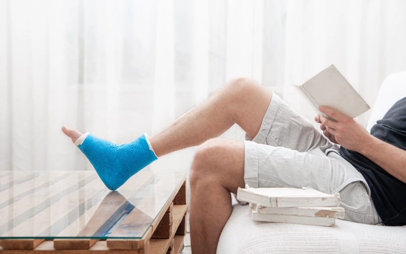 Hombre con la pierna escayolada leyendo un libro